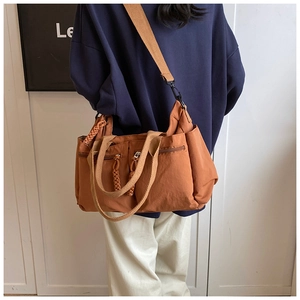 Detail view of caramel nylon multi-pocket tote bag with woven strap on model