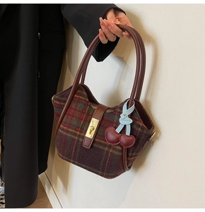 Détail du sac cabas vintage en laine à carreaux avec poignée en cuir et fermoir doré