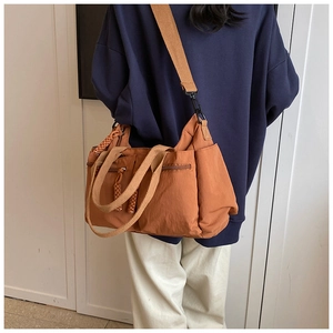 Close-up of orange multi-pocket tote bag with wide khaki strap on female model