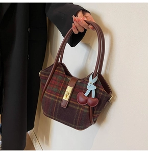 Détail du sac cabas en laine à carreaux avec poignées en cuir, fermoir et cerise décor