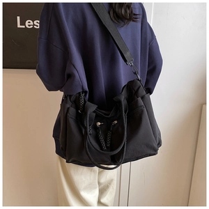 Detail of black multi-pocket crossbody bag with woven handles and utility zippers