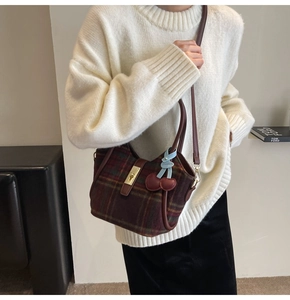 Détail du sac cabas rétro en laine quadrillée avec bordure en cuir et breloque cerise
