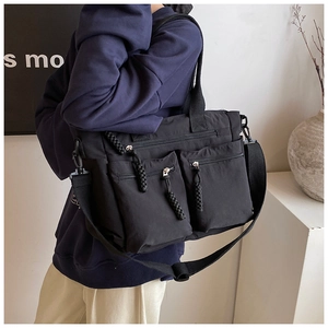 Detail of black multi-pocket canvas tote showing zipper texture and adjustable strap