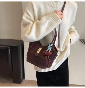 Détail du sac fourre-tout en laine à carreaux avec breloque cerise et fermoir doré