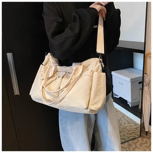 Close-up of cream canvas tote bag with multi-pocket design and adjustable wide shoulder strap
