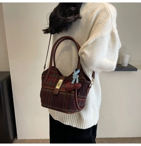 Détail du sac cabas en tweed à carreaux rouges avec fermoir rotatif et breloque cerise