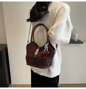 Détail du sac cabas en tweed à carreaux avec fermoir doré et pendentif cerise sur pull