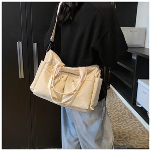 Detailed back view of a beige canvas multi-pocket tote bag worn on a model's shoulder