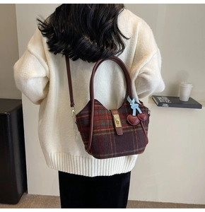 Détail du cabas vintage en laine à carreaux avec lanière en cuir et breloque cerise