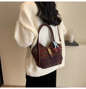 Détail du sac cabas en laine à carreaux avec garniture en cuir et breloque cerise