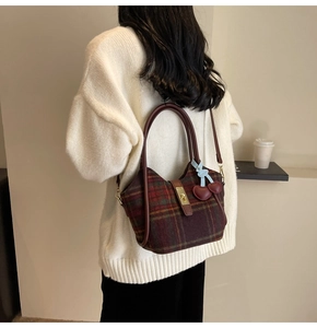 Détail du sac cabas en laine à carreaux rouges avec poignées en cuir et pendentif cerise