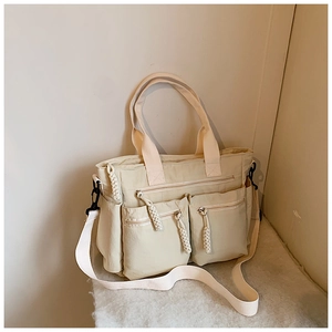 Close-up of cream white canvas tote bag with adjustable shoulder strap and multi-pocket design
