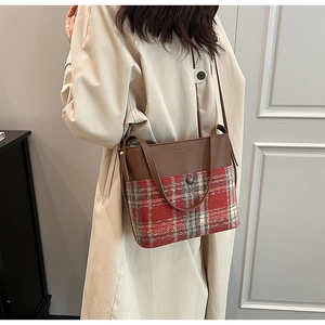 Détail du sac à bandoulière en cuir marron et tissu à carreaux rouges contrastés