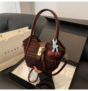 Détail du cabas en laine à carreaux dans un coffret cadeau avec poignées en cuir et breloque