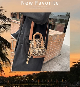 Dettaglio di borsa mini in finta pelliccia leopardata con tasca a zip e tracolla su cappotto