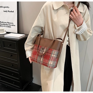 Détail d'un sac à main vintage en cuir marron et tissu à carreaux sur le mannequin