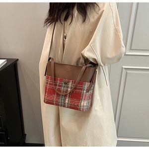 Détail d'un sac à bandoulière bicolore avec cuir marron et motif à carreaux classique
