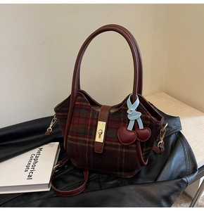 Détail du sac cabas en laine à carreaux avec fermoir doré et breloque cerise
