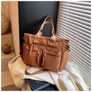 Detailed view of brown multi-pocket nylon tote bag with woven zipper pulls and side pockets