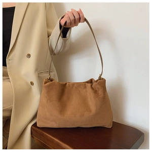 Brown suede Boston bag with vintage gold hardware on a wooden bench setting
