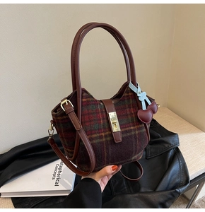 Détail du sac cabas en laine à carreaux avec poignées en cuir et breloque cerise