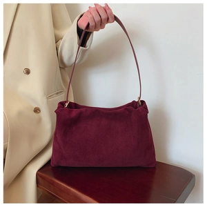 Detail view of burgundy suede Boston bag featuring long slim straps and gold metal hardware