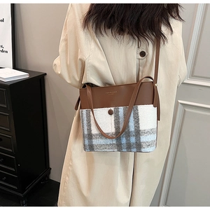 Détail d'un sac élégant combinant cuir marron et tissu en laine à carreaux bleus
