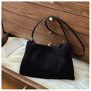 Detail view of black suede shoulder bag with gold hardware and elegant pleated texture