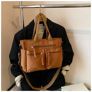 Macro detail of caramel nylon tote bag with functional zipper pockets and woven rope pulls