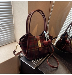 Détail du sac cabas en laine à carreaux rouges avec poignées en cuir et fermoir doré