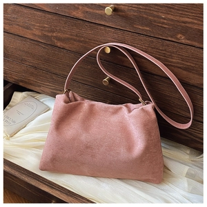 Detail of dusty pink suede Boston bag resting on silk inside a vintage wooden drawer