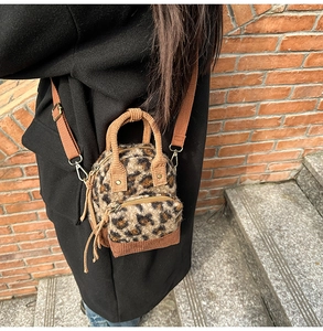 Dettaglio di un mini zaino in finta pelliccia leopardata indossato da una modella