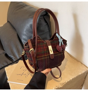 Détail du sac cabas en laine à carreaux rouges et verts avec poignées en cuir brun