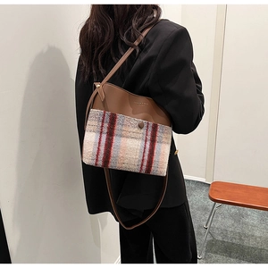 Détail du sac bandoulière rétro à carreaux en cuir sur une veste de tailleur noire