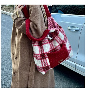 Outdoor shot of a red plaid plush tote bag with furry handles and a front pocket detail