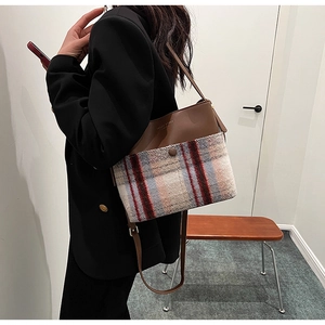 Détail de la texture en tweed à carreaux et cuir marron sur un sac seau élégant
