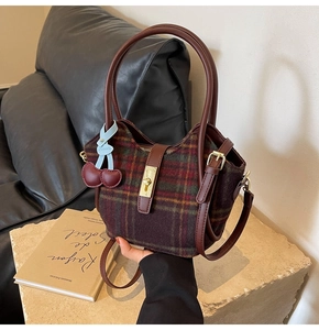 Détail du sac cabas en tweed à carreaux avec poignées en cuir et breloque cerise décorative