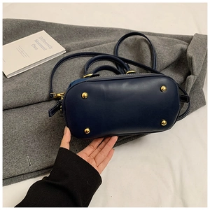 Close-up of dark blue contrast denim bag bottom with four golden protective metal studs