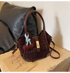 Détail du sac cabas en laine à carreaux vintage avec breloque cerise et dorures