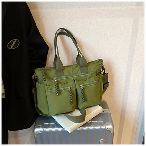 Detail of army green nylon multi-pocket tote bag placed on a silver suitcase