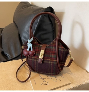 Détail du cabas en laine à carreaux avec fermoir doré et accessoire cerise rouge