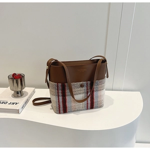 Détail des coutures en cuir et tissu à carreaux avec logo doré sur le sac à main