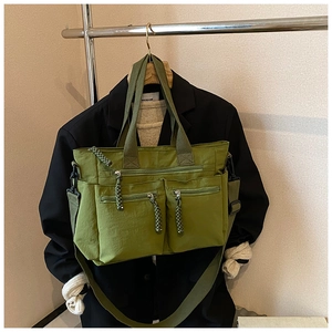 Detail of army green nylon tote bag with three zipper pockets and woven pullers