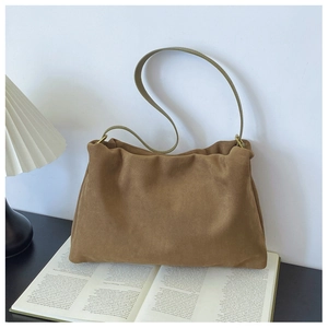 Close-up of brown suede Boston bag with sleek strap and minimalist pleat details