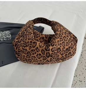 Detailed close-up of leopard print faux suede hobo bag on a minimalist white backdrop
