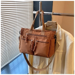 Detail view of brown multi-pocket tote bag with woven zipper pulls and wide strap