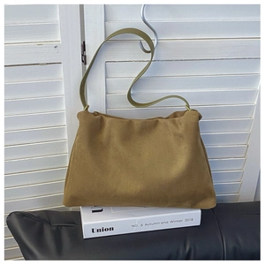 Detailed close-up of mustard yellow suede shoulder bag with elegant leather strap detail