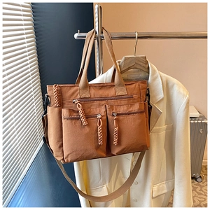 Detailed view of brown nylon tote bag with multiple zip pockets and knotted pullers