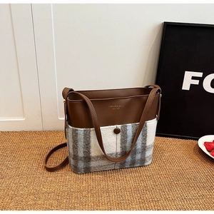 Détail du sac bandoulière en cuir marron et tissu à carreaux gris sur fond rustique