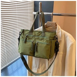 Close-up of grass green nylon tote bag with multi-pocket design on white blazer hanger